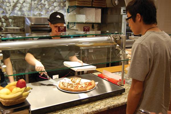 Elizabeth Brott, freshman in history, dishes up some pizza for Chendong Young at the new East Side Market located in the MWL commons Sunday afternoon. A new addition to the market is Godfather's Pizza that can be bought by the pizza or the slice. Photo: Jake Dickey/Iowa State Daily