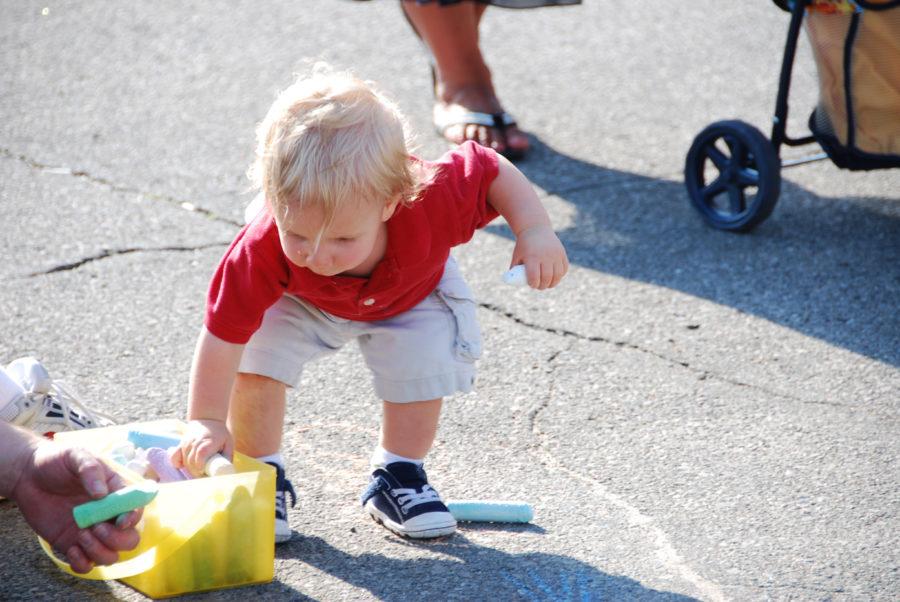 Connor Ritson, 1, draws with chalk Thursday at Tune In To Main Street.


