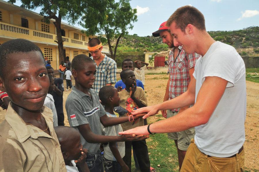Michael Vander Ploeg, background right, senior in architecture, and Drew Isbell, foreground right, play a hand game with some children during Bible school.