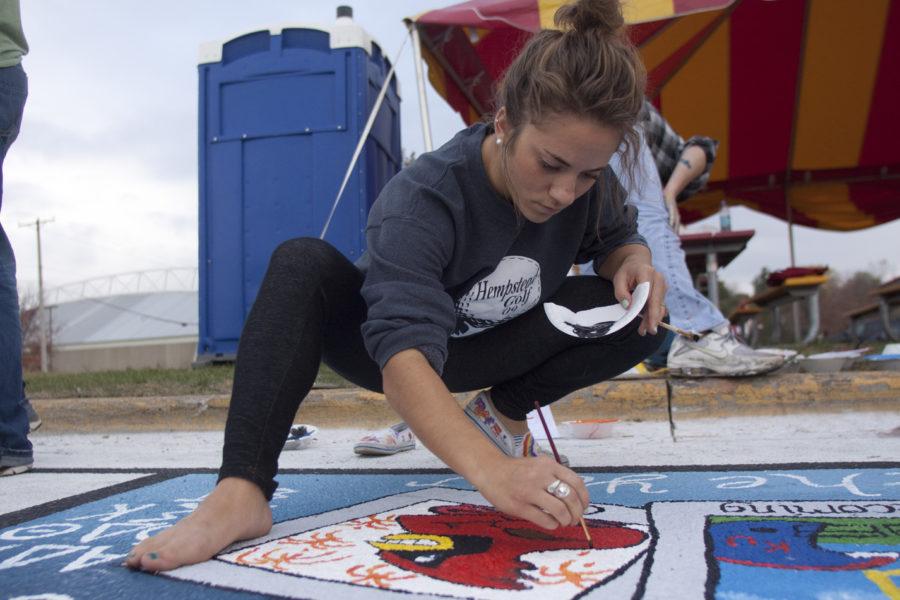 Jessica Muntz, freshman in apparel, merchandising, design and production, paints in the square that her teammates drew on Victory Lane on Sunday, Oct. 24, Iowa State Center parking lot. The squares on Victory Lane are open for any group that wishes to paint it.
