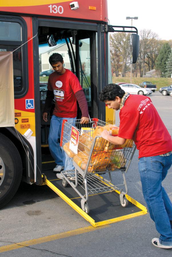 Indranil Roy, graduate student in computer engineering, helps Jagannathan Alagurajan, graduate student in biochemistry, push a cart full of donations Saturday onto a CyRide bus parked at West Hy-Vee. Volunteers accepted donations of nonperishable foods from shoppers as they left Hy-Vee.