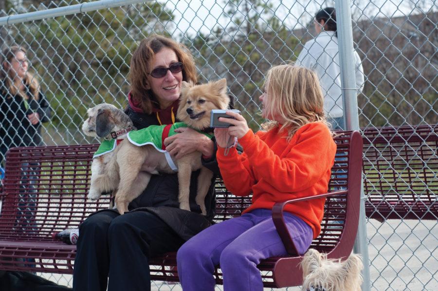 Karina Huisman, 11, shows her mother, Julie Huisman, a picture that she took of Bandit, a pomeranian, and Coco, a cavalier shih-tzu hybrid, during the Howl-O-ween Party, Sunday, Oct. 31, at Ames Dog Park. Both Bandit and Coco are dressed as Santas elves. 