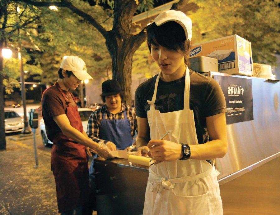 Jayson Hansen, right, senior in management, takes orders from customers, while Nicholas West, back right, ISU alumnus, places the orders with Albert Cho, junior in business and marketing. Hungry4Huh LLC sells the fusion-cuisine food in Campustown every Wednesday through Saturday night.