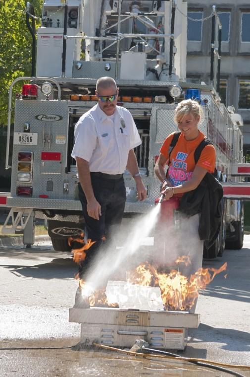 Kelsey Eischeid, left, freshman in kinesiology and health, puts out a fire with instruction by Lt. Brian OLoughlin of the Ames Fire Department on Friday, Sept. 17 near Kildee Hall.