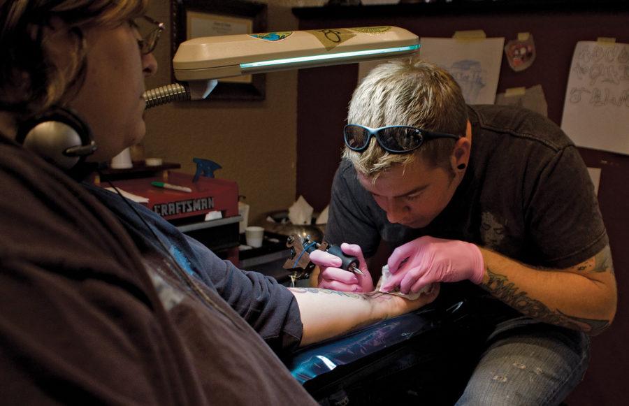 Berry Schnetter, tattoo artist at The Asylum, begins working on a breast cancer ribbon on Kris Lee, of Coon Rapids. Lee got the tattoo for her partner, who has the gene that makes it 80 percent more likely that she will get the disease, and who also had a double mastectomy.