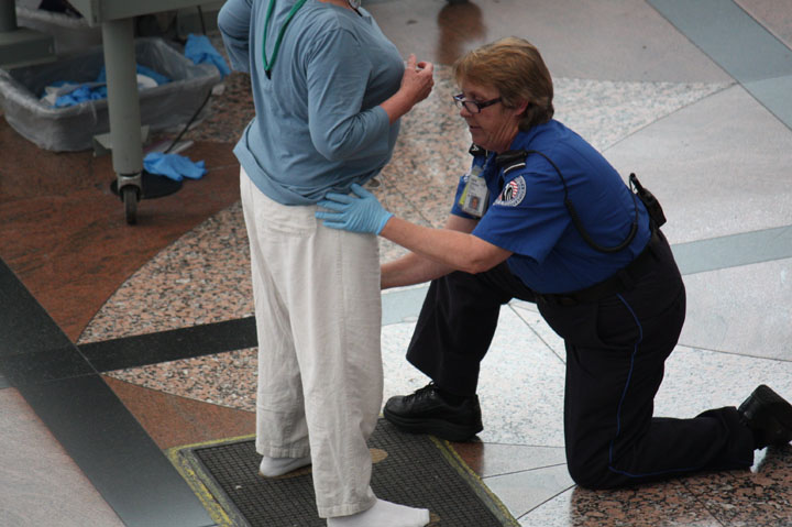 A TSA agent pats down female passengers at a Denver International Airport passenger screening point.