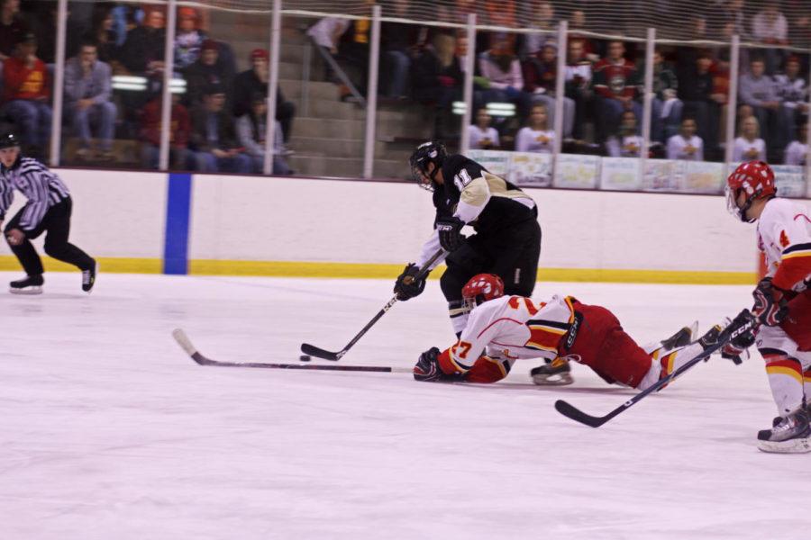 Forward Matt Cohn attempts to stop a Lindenwood opponent from advancing with the puck during the match Friday at the Ames/ISU Ice Arena. The Cyclones fell to the Lions 4-2.