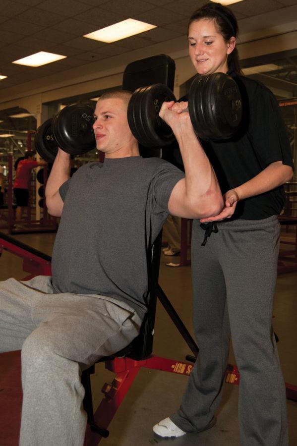 Austin Eppert, senior in kinesiology and health, holds a shoulder press while personal trainer Stephanie Spotts, senior in kinesiology and health, helps spot at Lied Recreational Athletic Center. Spotts has been a personal trainer at Lied since May of last year after receiving national certification last April.