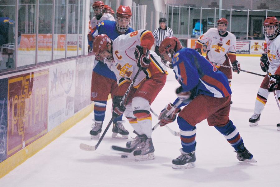 Captain Cort Bulloch attempts to protect the puck from a Kansas opponent during the hockey game Friday at the Ames/ISU Ice Arena. The Cyclones defeated the Jayhawks 9-0. 