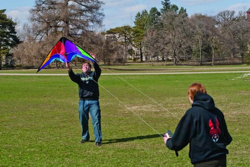 Dustin Simmons, junior in civil engineering, hoists a kite Sunday on Central Campus for Michelle Brus, freshman in agricultural engineering, who was curious to see how high the kite can fly. 