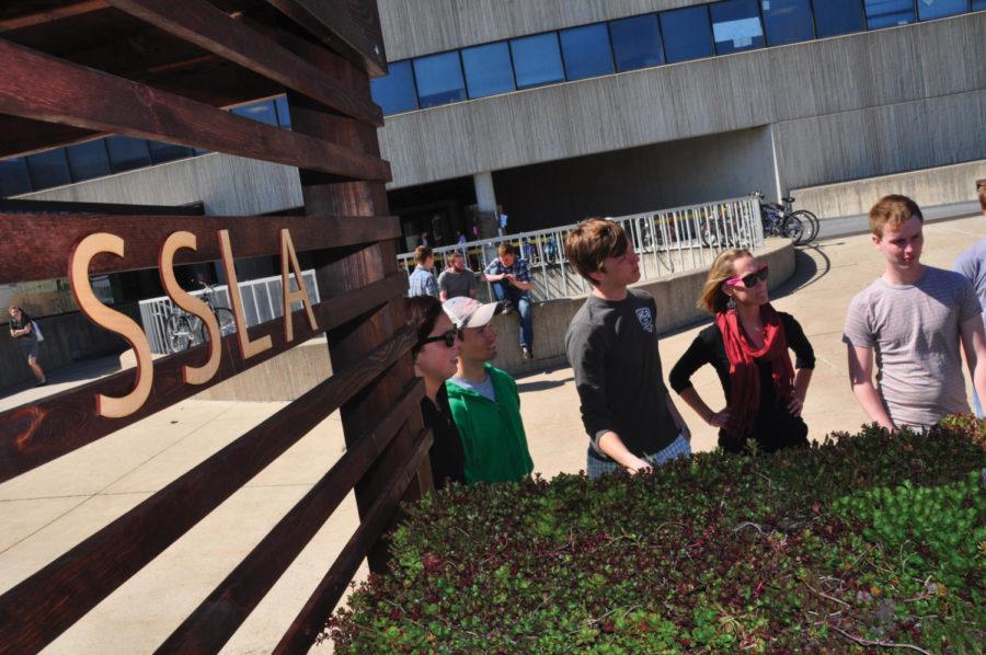 Members of the Student Society of Landscape Architects stand around their model green roof Monday in front of the College of Design. The model was constructed to teach VEISHEA visitors about green design and sustainability, and to draw attention to the two green roofs on campus.
