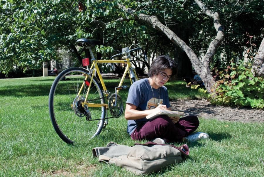 Brandon Persson, junior in architecture, enjoys a book and
sketching outside of Parks Library on Monday.

