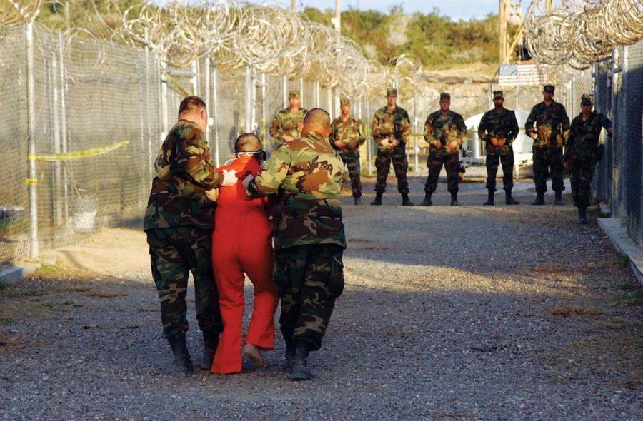 Two US Army Military Police escort a detainee, dressed in an
orange jumpsuit, to a cell at Camp X-Ray, Guantanamo Bay Navy Base,
Cuba. Camp X-Ray is the holding facility for detainees held at the
US Navy Base during Operation Enduring Freedom. Photo by Mate 1st
Class Shane T. McCoy
