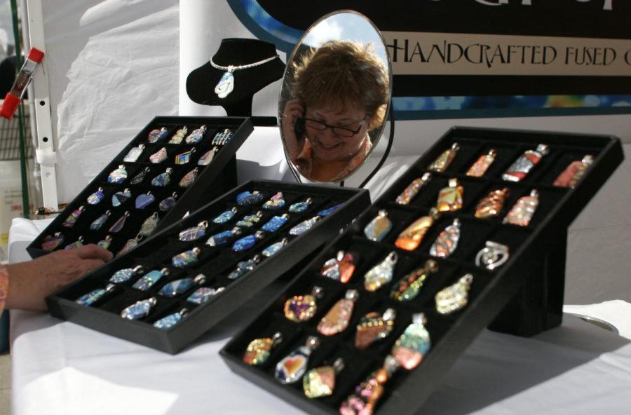 Leslie Saftig, of Ames, talks on the phone while looking at
jewelry at the Touch of Glass booth at the Octagon Art Festival
Sept. 25, 2011 in downtown Ames. Saftig loves connecting with the
people in the community at the festival, and has been coming for
nine years.
