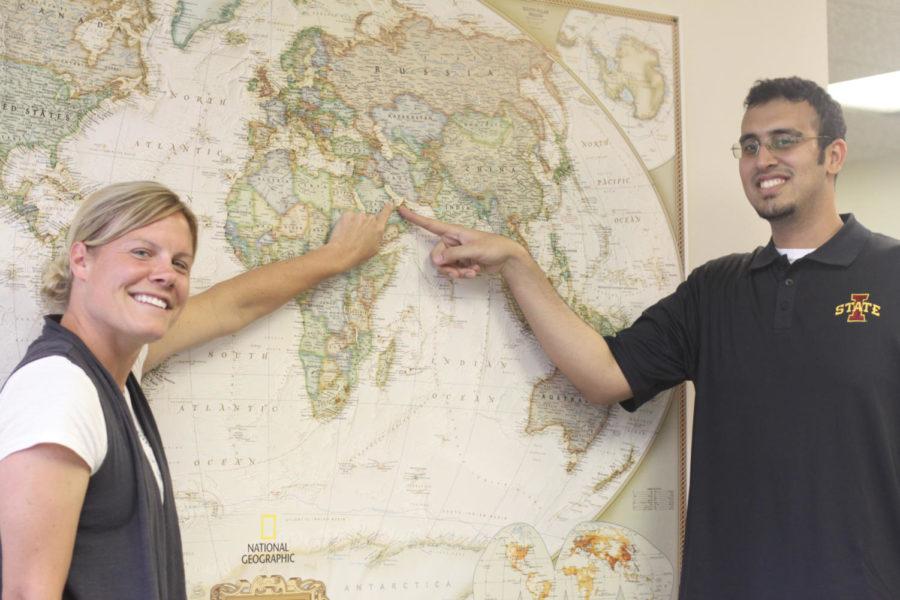 Lana Seiler, administrative specialist of International Students
and Scholars, and Ahmad Al-Saygh, senior in community and regional
planning, point at a world map. 
