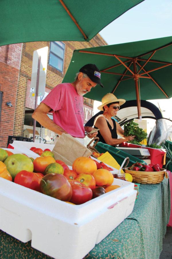 Jon Lynch and Lonna Nachtigal, of Onion Creek Farms, organize their goods at the Ames Famers Market on Saturday, Aug. 27. The Ames Farmers Market hosts a variety of stands, all of local flavor.  
