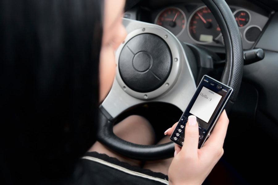 Young woman typing text message while driving
