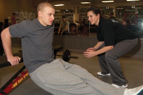 Austin Eppert, senior in kinesiology and health, gets help with his squatting excercises while personal trainer Stephanie Spotts, senior in kinesiology and health, helps coach at the Lied Recreational Athletic Center. Spotts has been coaching at Lied since May of last year after receiving national certification last April.
