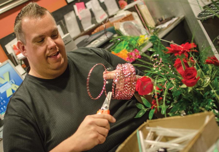 Dan Brabec, owner of Coes, continues working on a flower arrangement amidst the celebration during Coes 80th anniversary on Thursday, March 22. Brabec has owned the Coes business for 10 years, after working with flower decoration 10 year prior.
