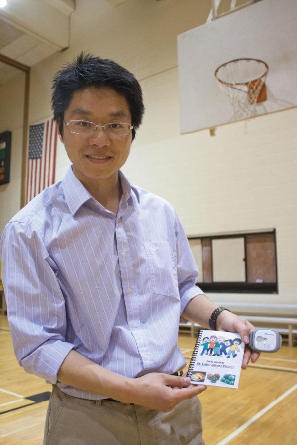 Senlin Chen, assistant professor of kinesiology, displays the Sense Wear armband and food journal used in his research on middle school students Tuesday, April 24, at Forker Hall.  The armband is used to determine how much energy the subject expends.  
