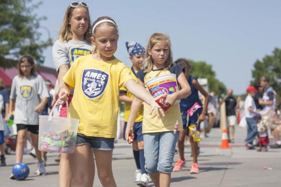 A girl from the Ames Soccer Club throws candy to people crowding the curbs of Main Street Ames on Wednesday, July 4, for the Independence Day parade. In addition to the traditional handing out of candy, spectators at the parade picked up yard sticks, rain water gauges and bottles of water.
