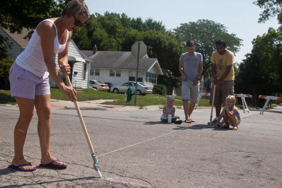 Neysa Goodman and her family help Nitin Gadia, co-founder of the Ames Street Art project, draw the initial boundary for the street design on Saturday, Jun. 30, at the corner of South Wilmoth Ave. and Lettie St. in Ames. Gadia started the project as a way to bring the community together and express themselves in a public space.
