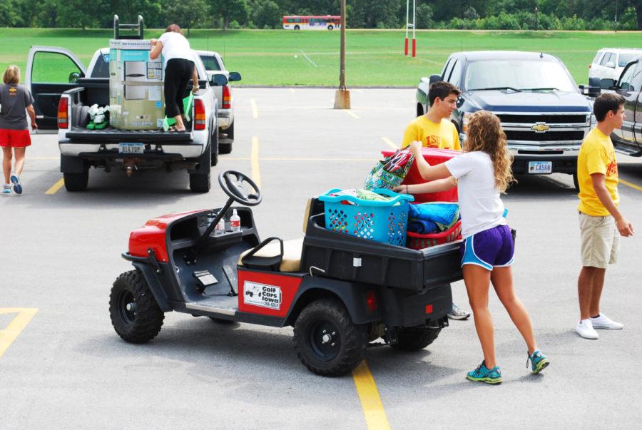 Move-in crew members help students move their belongings using golf carts. 