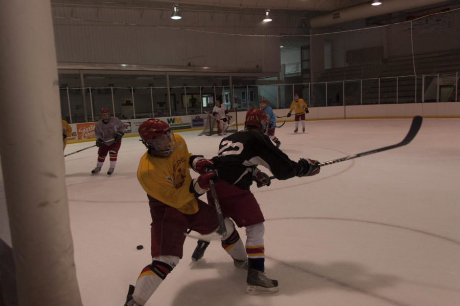J.P. Kascsak, in yellow, freshman in kinesiology and health, finishes his hit against Scott Antonsen, in black, freshman in pre-business, during practice Wednesday, Sept. 19, at the Ames/ISU Ice Arena.
