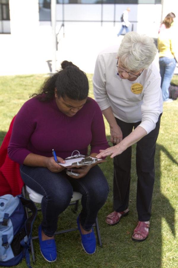 Jane Halliburton helps Teonna Flipping, senior in communications, register to vote at the Leage of Women Voters table Tuesday, Sept. 25, outside Parks Library.
