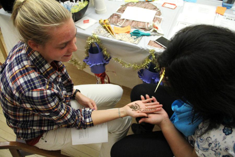 Presha Kardile, junior in management, uses henna to draw an Indian design on Taylor McDowell, freshman in anthropology, during an International Bazaar on Wednesday, Nov. 14, in the Gallery Room at the Memorial Union. International students came together to put on a bazaar that presented a variety of cultural displays, arts and crafts, foods, and drinks.
