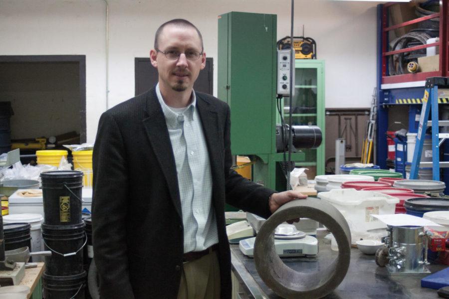 Jason White, professor of engineering, stands next to his new type of sewer pipe made of recycled plastics and fly ash.

