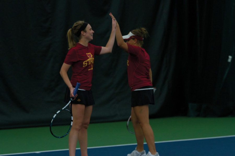 ISU junior Jenna Langhorst, left, is happy as she high-fives her teammate Ksenia Pronina after they won a tough volley against Kansas State on Friday, April 13. The duo lost 8-3. The event took place indoors at the Ames Racquet and Fitness due to weather conditions. 

