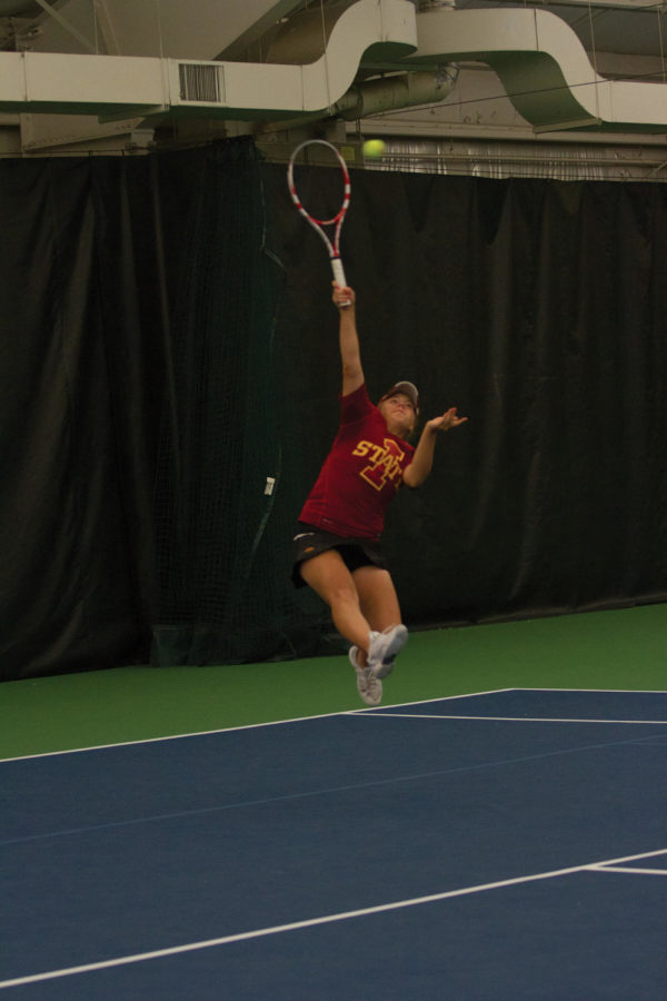 Ksenia Pronina reaches to hit the ball as it flies over her in doubles play against Kansas State on Friday, April 13. Pronina was paired with junior Jenna Langhorst for the match and the team fell to Kansas State with a final of 8-3. The event took place indoors at the Ames Racquet and Fitness due to weather conditions.
