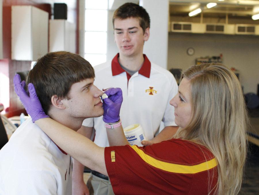 Kayla Kleihauer, a graduate student in educational leadership and policy studies as well as an athletic trainer, demonstrates the procedure to fix a bloody nose on Eric Bornholdt, junior in athletic training, while Billy Lutz, junior in athletic training, aids Kleihauer by applying skin lube to the nose plug on Feb. 12 at Lied Recreation Athletic Center. These three athletic trainers will attend the state of Iowa wrestling tournament in downtown Des Moines to aid wrestlers who need any medical treatment, ranging from bloody noses to concussions.
