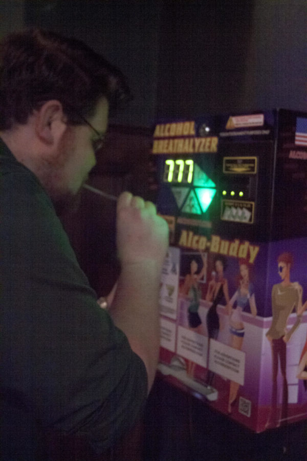 Ben Wichtendahl, a patron at Charlie Yokes, demonstrates how the newly installed wall-mounted breathalyzer is used.
