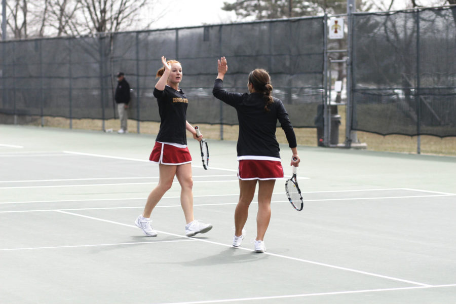 Meghan Cassens high-fives her teammate Simona Cacciuttolo after they score in their doubles game against Oklahoma State University on Sunday, April 7, 2013, at the Forker tennis courts.
