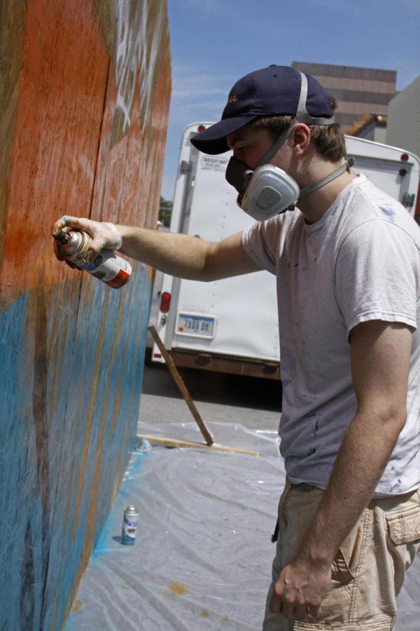Walker Williams dons a gas mask to prevent fume inhalation as he spray-paints a sheet of plywood for a live graffiti art display at the 2013 515 Alive music festival in downtown Des Moines, on August 3.