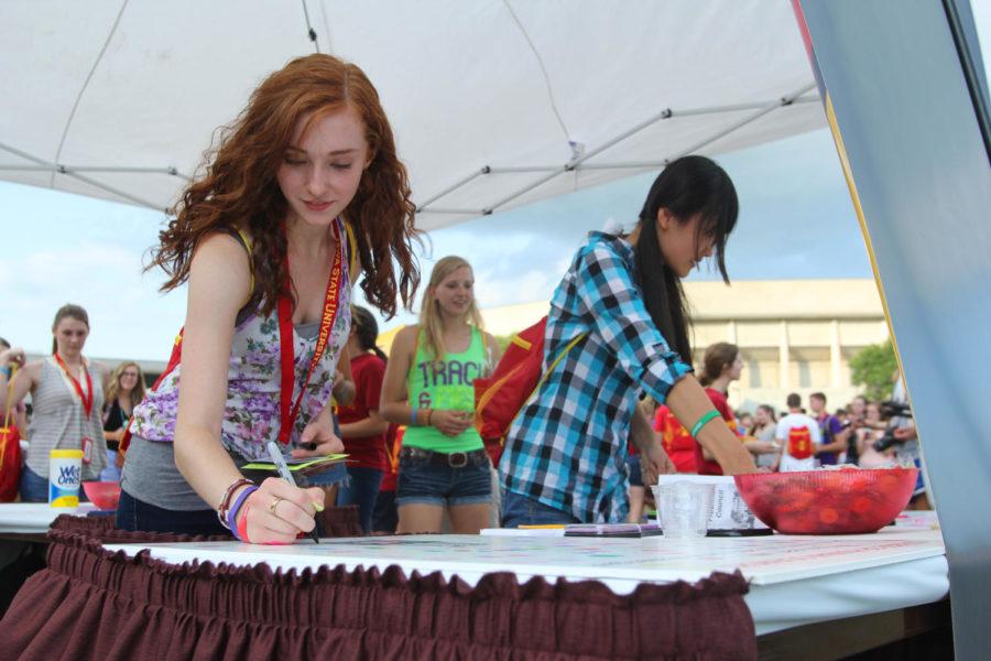 Nutritional Science sophomore Jenna Hrdlicka signs her name on her inked thumb print that she placed on a poster at the College of Human Sciences tent on August 22, 2013. Students signed their thumb prints on a poster which said This year I will set my sights high and rise to challenges! The activity was part of the Center of ExCYtment in the Scheman Courtyard next to Hilton Coliseum. 