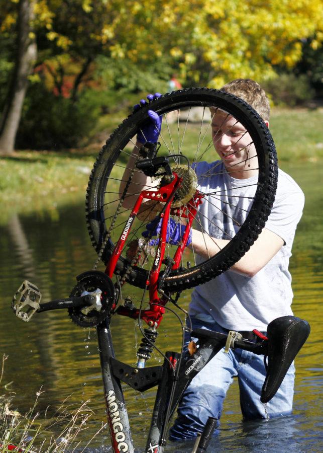 Tommy Ryan, freshmen in mechanical engineering, wades into Lake LaVerne to pull out a bike on Sunday, Oct. 13, for Greeks Go Green cleanup.