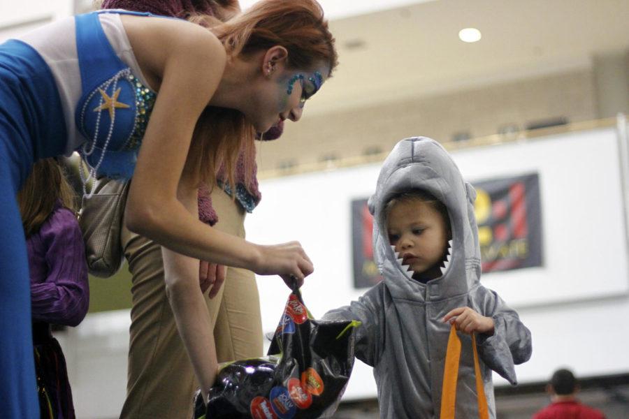 Lexxi Manassa, sophomore in business, hands candy to Tallis Garcia, 3, as part of the ISU greek community’s trick or treat night for the Ames community Tuesday at Howe Hall.