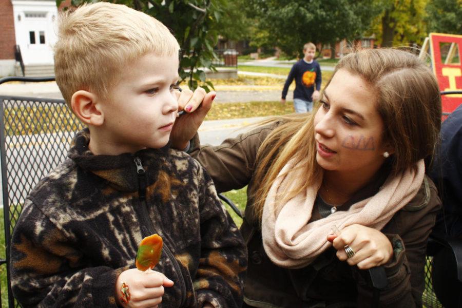 Caroline Schmidt, freshman in psychology, paints 4-year-old Michael Kundels face on Sunday out on the Sigma Alpha Epsilon lawn.