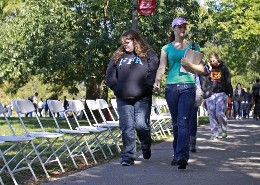 Passersby examine Violence Leaves An Empty Chair at the Table, a display of about 200 chairs lining the sidewalk from the Sloss House to the Memorial Union. Each chair represented a person killed by interpersonal violence in Iowa since Jan. 1, 1995, and told their story. The event was a joint effort put on by the Sloss House and the Assault Care Center Extending Shelter and Support, the latter of which provided resources and information about domestic violence.