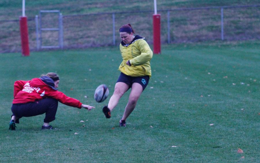 Teagan Hughes, junior in environmental science, practices kicking a field goal before Iowa States womens rugby club team practice while Alysha Gareis, graduate student in animal science, holds the ball. 