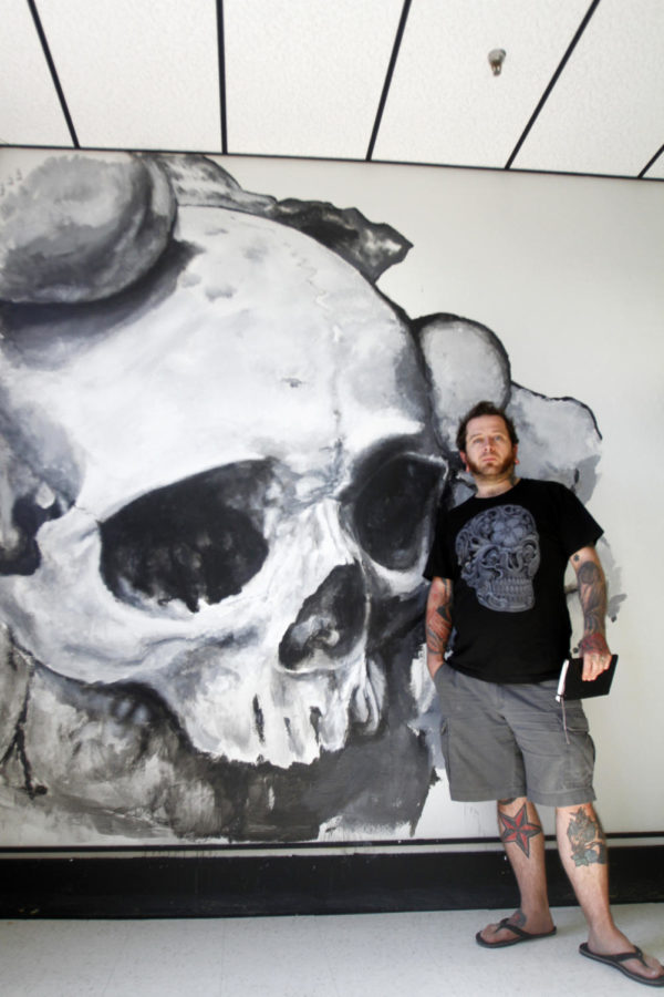 Daniel Rainey Forrester stands in front of his mural inside Inkblot Studio on Friday, Sept. 27. Daniel plans on expanding the mural further across the wall.