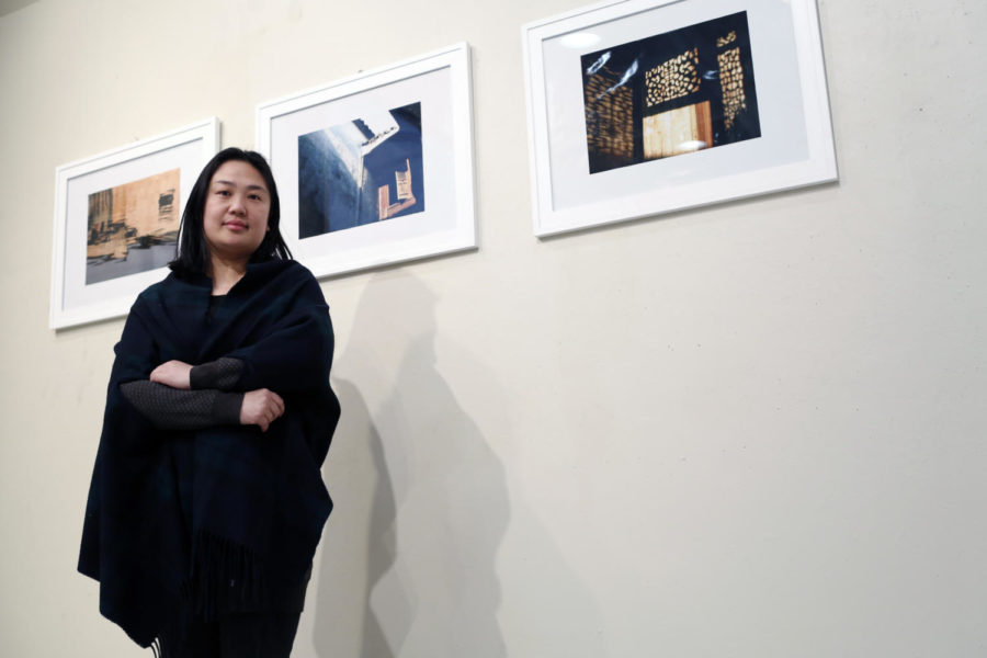 Wang Xin, graduate from Wuhan University, poses with framed prints of her photography that is hanging in the Gallery Room in the College of Design building.
