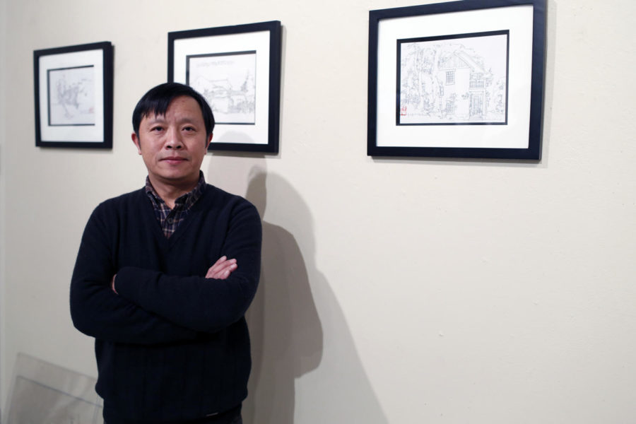 Wen Qingwu, associate professor and vice dean at the Wuhan University, poses with his drawings which are hanging in the Gallery Room in the College of Design building.