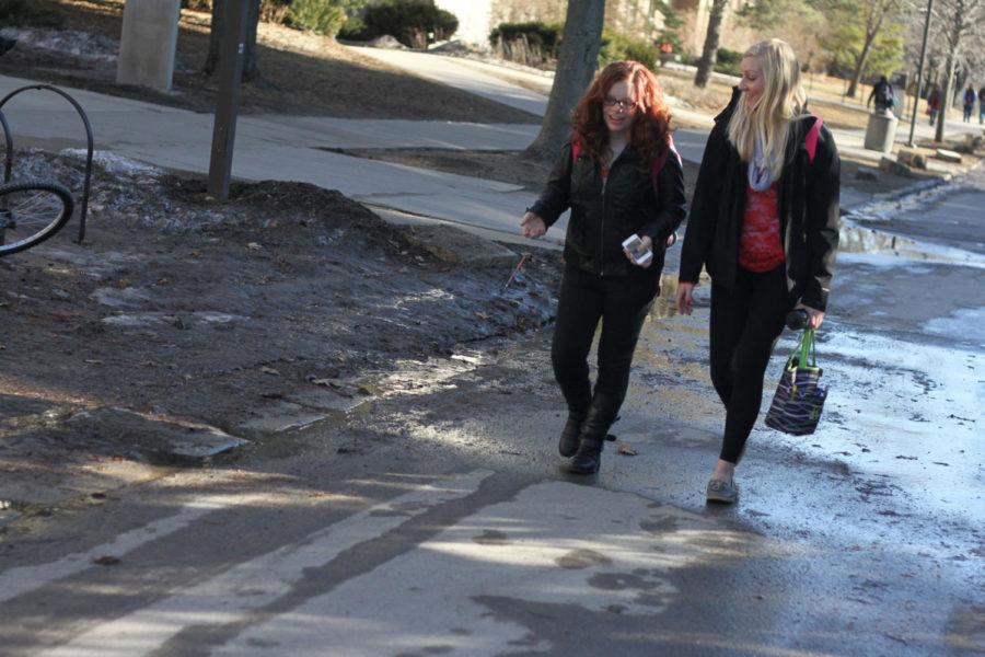 English education majors Emma Rodenburg, left, and Kristen Ahlers walk through mud that can be found throughout campus.