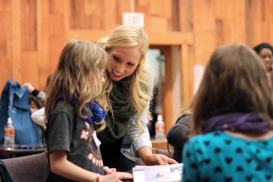 Members of the Fashion Show hosted hands-on crafts March 8 with members of the Girl Scouts. Courtney McCulloh, junior in event management, helps a Girl Scout with her collage.