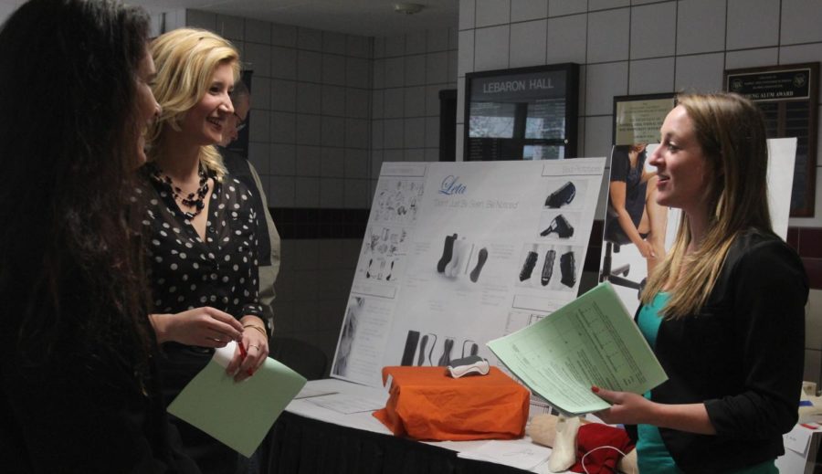 Lana Miller, senior in industrial design, presents her business plan for In Joy to Shelby Schmidt, middle, junior in apparel, merchandising and design, and Andrea Schmidt in the LeBaron Hall lobby May 1.