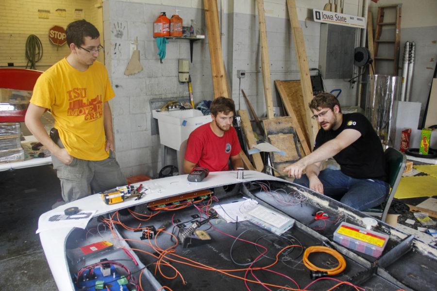 Danny Goldman, left, and Ryan Hupp, middle, seniors in aerospace engineering, and Jonathan Bauer, graduate in mechanical engineering, work on the solar car Phaeton on June 28 in the Team PrISUm garage in Sweeney Hall. 